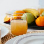 Bright and fresh breakfast setup featuring orange juice and a variety of fruits on a neatly arranged table.
